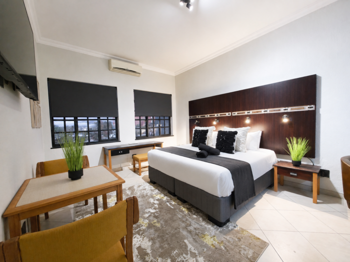 Luxury studio apartment at Promenade Place in Nelspruit with king-size bed, work desk and dining area.